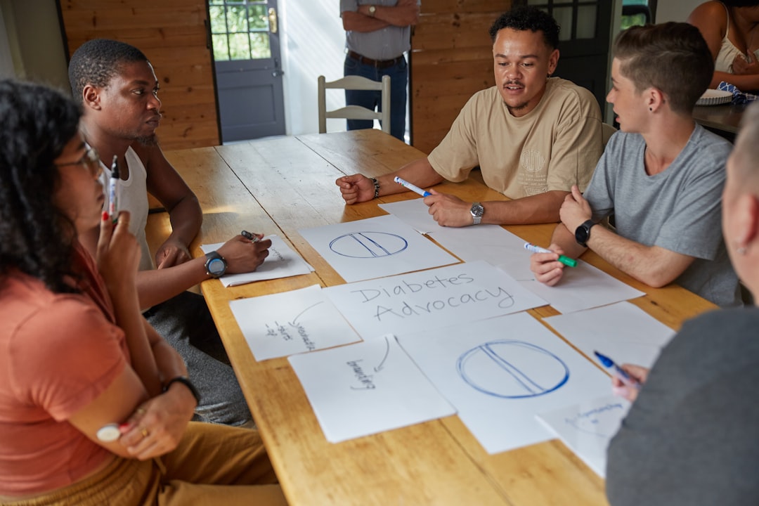 A diverse team of colleagues sitting around a large table in a professional setting, engaged in a collaborative discussion and working together on a project.