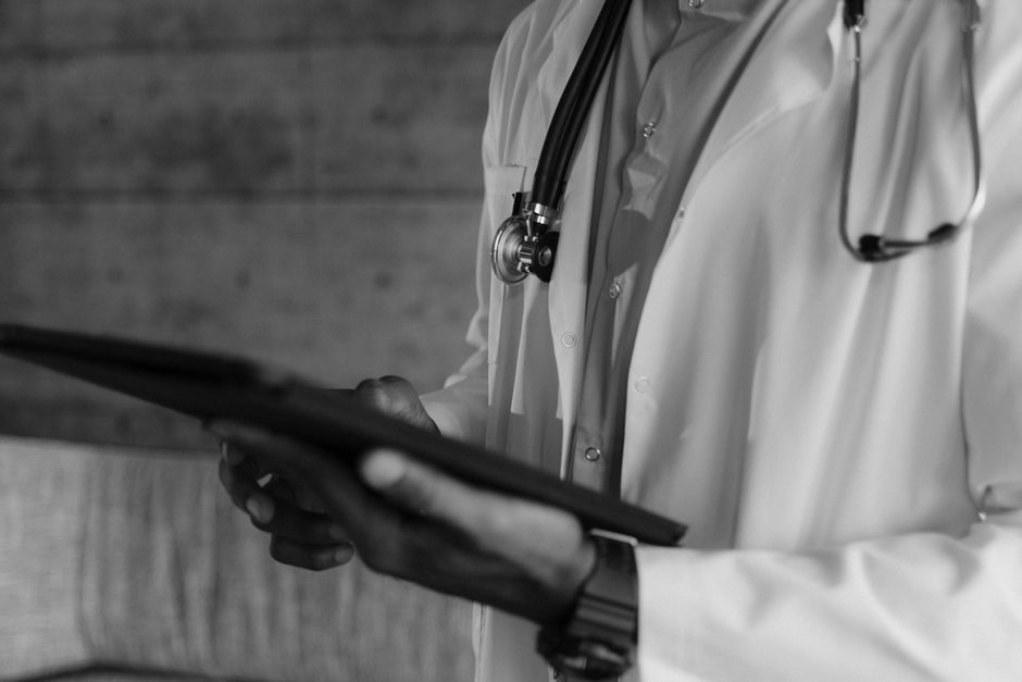 A professional and friendly doctor in a modern, clean clinic, using a digital tablet to review patient information or educational materials.
